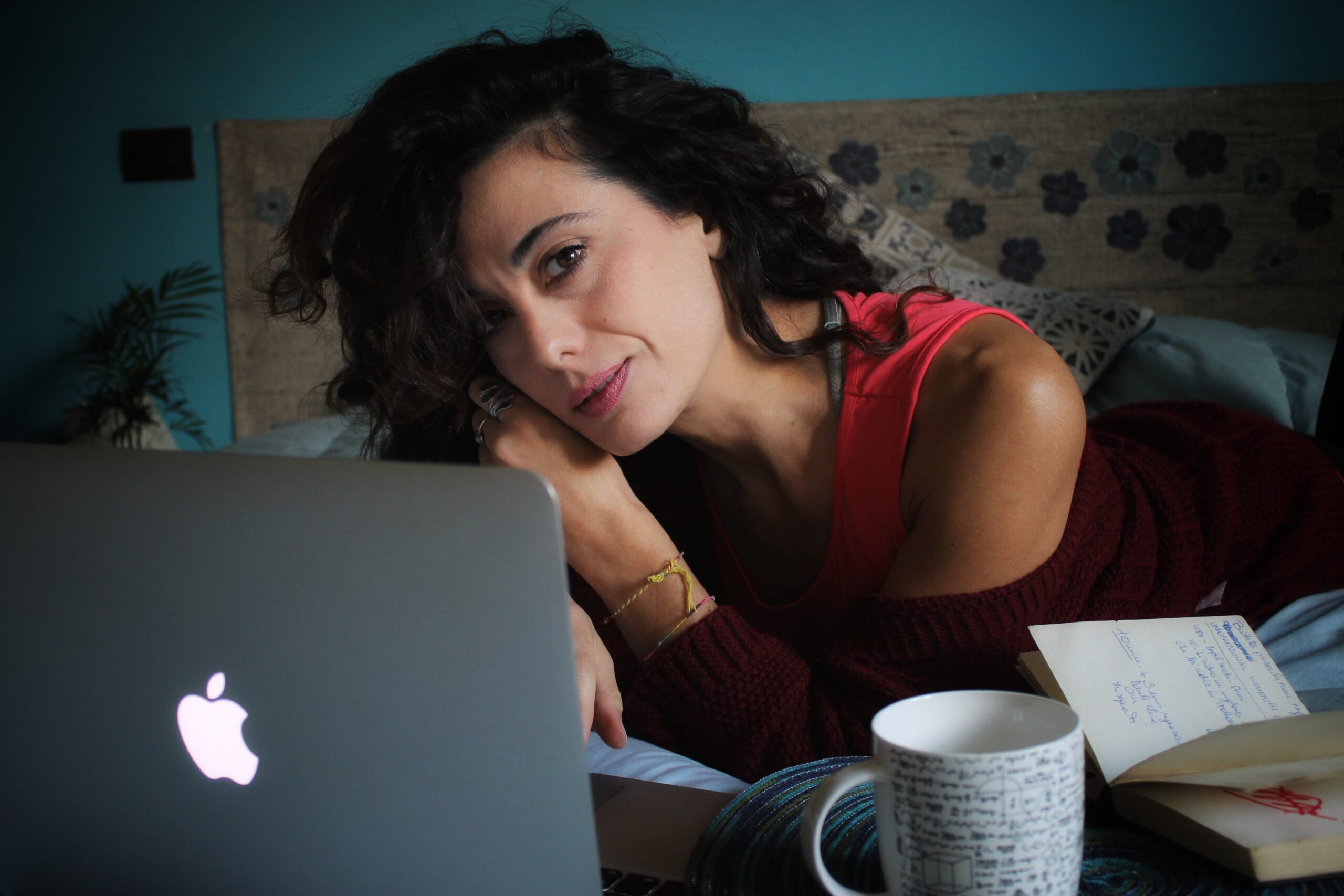 sabrina su letto con computer acceso e sfondo sfocato parete blu