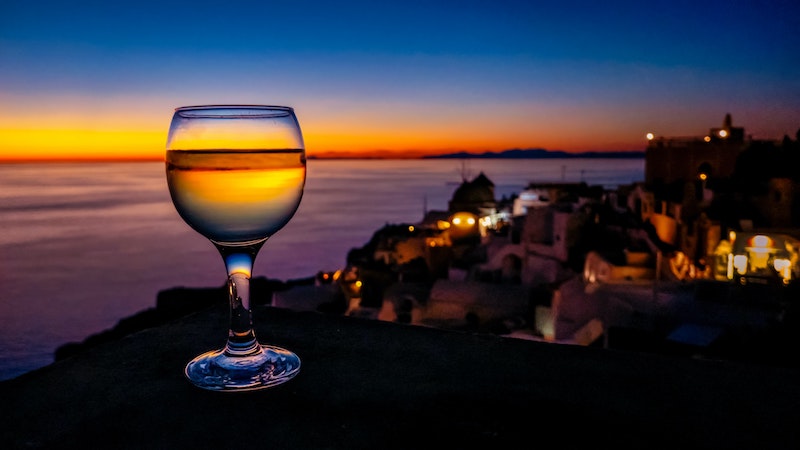 bicchiere di vino con sfondo tramonto a santorini 
