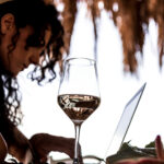 sabrina al computer con un calice di vino in primo piano